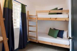 Doppel-Stockbett im Zimmer des Veranda Pointe Aux Biches Hotels mit grünen und blauen Kissen und weißen Laken.