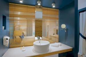Badezimmer im Veranda Pointe Aux Biches Hotel mit weißem Waschbecken und blauen Wänden.