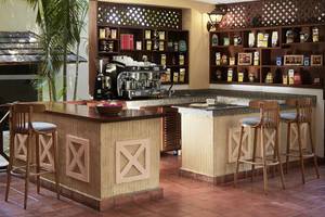 Barbereich im Neptune Beach Resort in Kenia mit Holzbar, Hockern, Kaffeemaschine und Regalen.