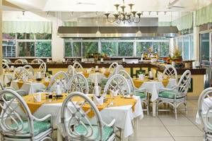 Innenansicht des Restaurants im Neptune Beach Resort in Kenia mit gedeckten Tischen und Stühlen.