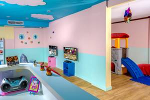 Ein farbenfrohes Kinderzimmer im Best Western Premier Bangtao Beach Resort mit Fernseher, Bücherregal und Spielzeug.