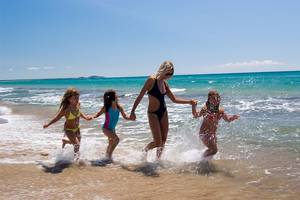 Mutter und Töchter am Strand von Verde Al Mare Hotel spielen im Wasser