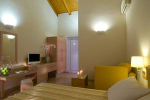 Schlafzimmer im Hotel Verde Al Mare mit Bett, Schreibtisch, Stuhl und gelbem Sofa.