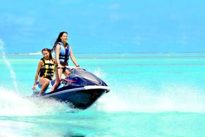 Zwei Frauen fahren auf einem Jetski im blauen Ozean und genießen die Fahrt.
