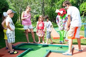 Kinder spielen Golf im Freien am Belconti Resort mit Clowns als Begleiter.