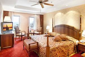 Ein elegantes Schlafzimmer im Belconti Resort Hotel mit Doppelbett, Fernseher und Dekor.