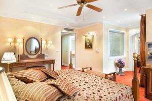 Ein elegantes Schlafzimmer im Belconti Resort mit einem großen Bett, einem Spiegel, einem Schreibtisch und einer Deckenventilator.