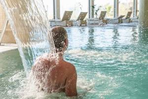 Mann im Pool unter einem Wasserfall im Secrets Bahia Real Resort & Spa