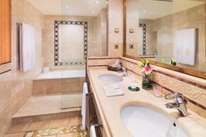 Luxuriöses Badezimmer mit Doppelwaschbecken, Badewanne, Spiegel und Marmorboden.
