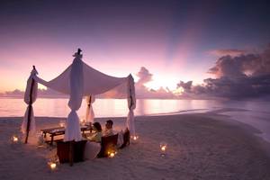 Zwei Personen genießen ein Abendessen unter einem Zelt am Strand des Waldorf Astoria Dubai Palm Jumeirah.