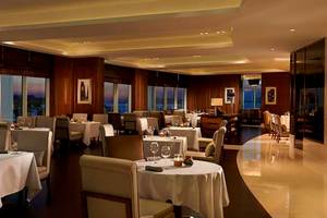 Innenansicht des Restaurants im Waldorf Astoria Dubai Palm Jumeirah mit elegant eingerichteten Tischen und Stühlen.