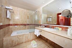 Ein Badezimmer im Bahia Principe Grand Turquesa mit Badewanne, Dusche, Waschbecken und Spiegel.