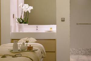 Spa-Behandlungsraum im Capo Bay Hotel mit Tisch, weißen Vasen und Orchideen.