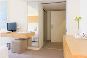 Inneneinrichtung eines Zimmers im Capo Bay Hotel mit Schreibtisch, Spiegel, Pflanzen und Betten.