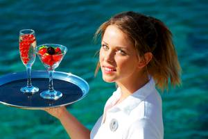 Frau mit Cocktails am Strand vor dem Petasos Beach Resort & Spa