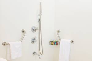Barrierefreie Dusche im Capo Bay Hotel mit Handtüchern und Haltegriffen.