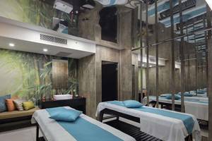 Massageraum im Magic Life Belek Hotel mit blauen und weißen Laken, Kissen und Bambusmotiv an der Wand.