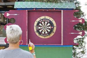Eine Person spielt Darts vor einem Dragon Dartboard.