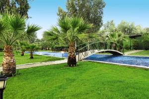 Garten des Palm Wings Ephesus Beach Resorts mit Brücke und Palmen