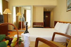 Hotelzimmer im Palm Wings Ephesus Beach Resort mit Bett, Obstkorb und Weinflasche.