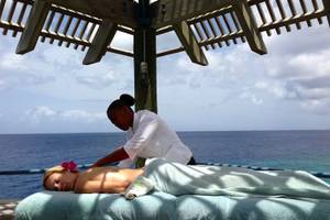 Eine Frau genießt eine Massage im Freien unter einem Pavillon mit Blick auf das Meer.