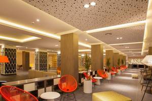 Innenbereich des Abora Catarina Hotel mit roten Stühlen und Tischen, Pflanzgefäßen und gefliestem Boden.