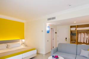 Innenansicht eines Zimmers im Abora Catarina Hotel mit Bett, Sofa, Tisch und Kleiderschrank.