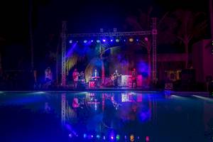 Ein abendliches Konzert am Pool des Kandima Maldives Hotels mit bunten Lichtern und Musikern auf der Bühne.