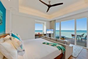 Luxuriöses Hotelzimmer mit Meerblick im Kandima Maldives, mit Kingsize-Bett, Wohnzimmerbereich und Terrasse.