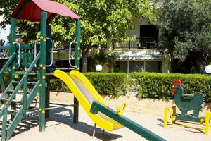 Spielplatz vor dem Hotel Acrotel Athena Pallas mit Rutsche und Hühnerfigur.