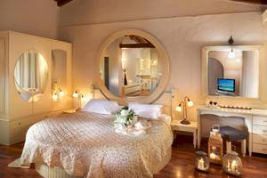 Schlafzimmer im Acrotel Athena Pallas Hotel mit großem Rundspiegel und Fernseher im Spiegel.