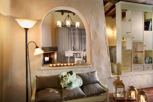 Innenansicht eines Zimmers im Acrotel Athena Pallas mit Couch, Kamin und Dekor.