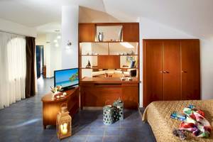 Innenansicht eines Hotelzimmers im Acrotel Athena Pallas, mit Bett, Fernseher, Schrank und Dekor.