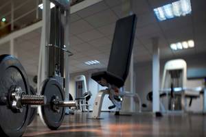 Fitnessstudio mit Gewichten und Fitnessgeräten wie einer Bank und einem Hantelständer