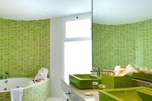 Badezimmer im Vincci Tenerife Golf Hotel mit grünen Wänden, Badewanne und grünen Waschbecken.