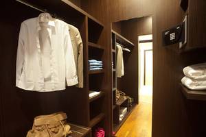 Innenansicht des Garderobenbereichs im Elysium Resort & Spa mit gut gefüllten Kleiderschränken, Schuhen und Handtasche.