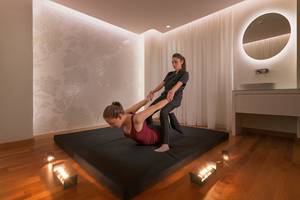 Eine Frau assistiert einer anderen Frau bei einer Yoga-Sitzung im Elysium Resort & Spa.