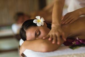 Frau erhält Massage im Elysium Resort & Spa mit einer Blume im Haar.