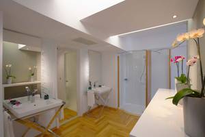 Elysium Resort & Spa Badezimmer mit Dusche, Waschbecken und Orchideen.