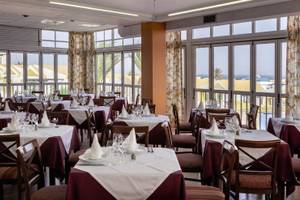 Innenansicht des Restaurants im Club Caleta Dorada mit gedeckten Tischen und Blick auf den Außenbereich.