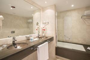 Ein elegantes Badezimmer im Hipotels Cala Millor Park mit zwei Waschbecken, einem Spiegel und einer Dusche.