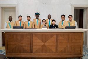 Empfangsteam des St. Regis Saadiyat Island Resorts vor dem Empfangstresen