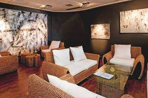 Lounge-Bereich im Playa Golf Hotel mit schwarzen Wänden, großen Gemälden und Korbmöbeln.