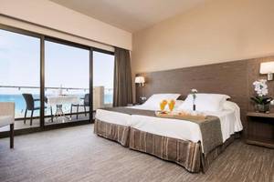 Zimmer im Playa Golf Hotel mit Meerblick, inklusive Bett, Schreibtisch und Balkon mit Tisch und Stühlen.
