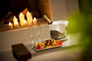 Ein romantisches Badewannenerlebnis im Kipriotis Village Resort mit einer Flasche Champagner, zwei Gläsern und einem Obstteller.