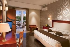 Hotelzimmer im Kipriotis Village Resort mit Terrasse, Bett und Wohnzimmermöbeln.