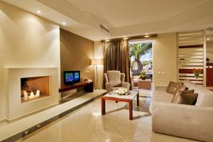 Wohnzimmer im Kipriotis Village Resort mit Fernseher, Kamin und Sofa.