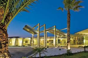 Außenansicht des Kipriotis Village Resort Hotels bei Nacht mit Palmen und Lichtern.