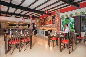 Innenansicht des Restaurants im Riu Lupita Hotel mit gedeckten Tischen und einer servierenden Mitarbeiterin.