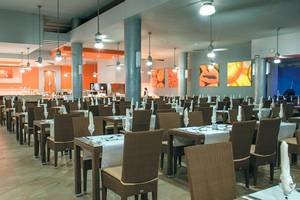 Restaurant des Riu Lupita Hotels mit gedeckten Tischen und Stühlen, Deckenventilatoren und Kunstwerken.
